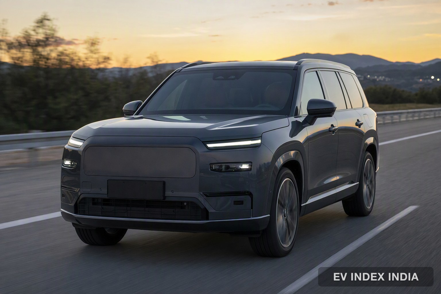 A large dark grey electric SUV on a highway at dusk